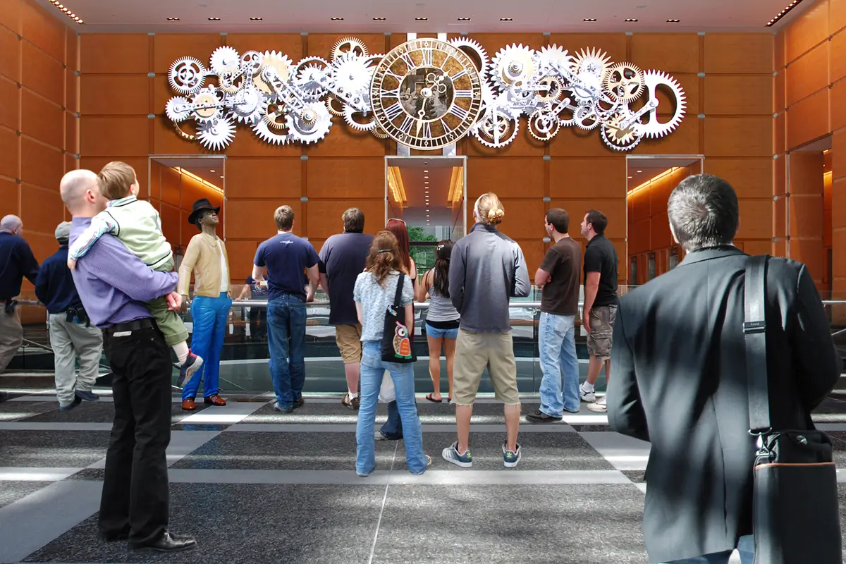 People observing intricate clock installation in lobby.